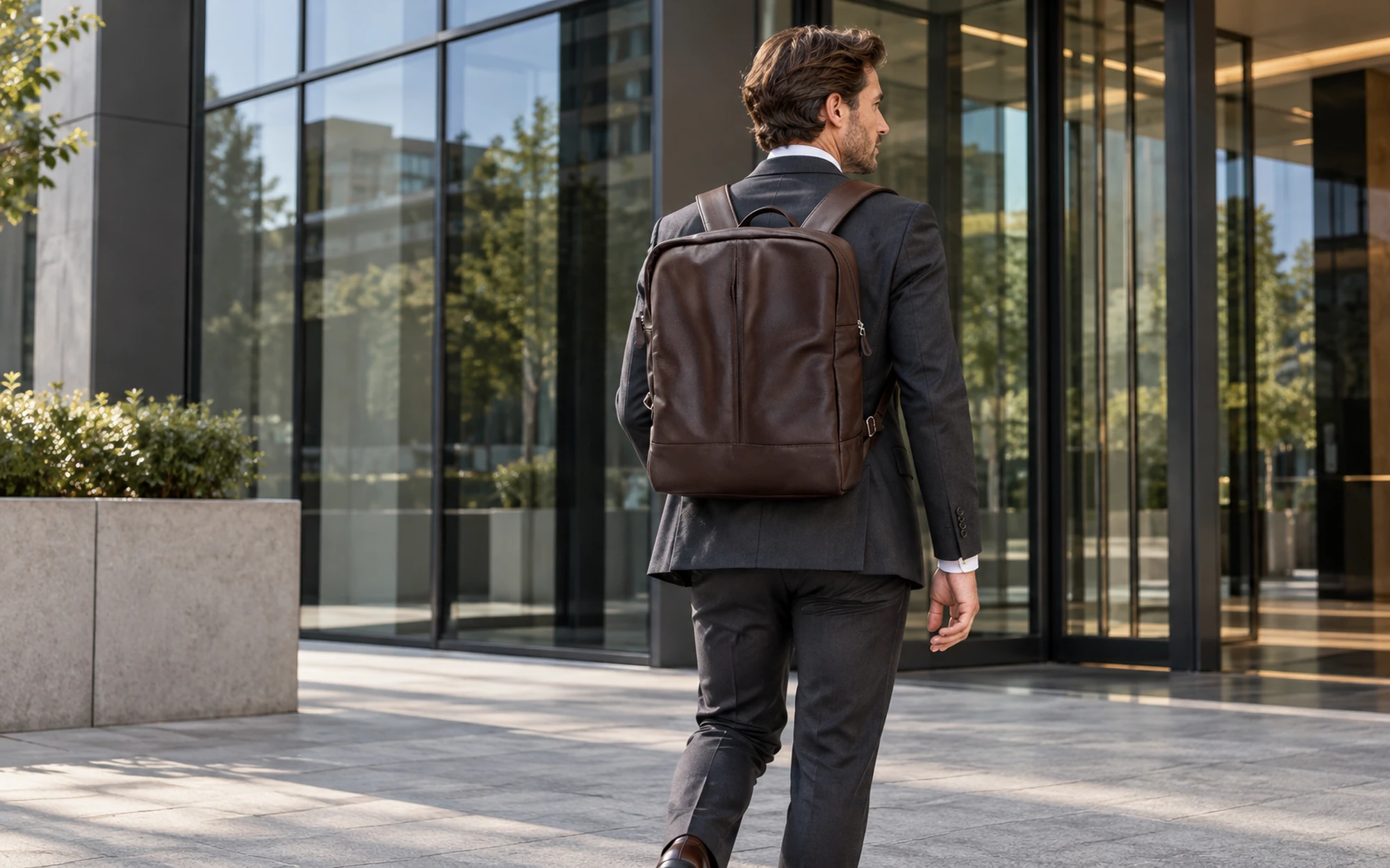 Executivo chegando a edifício corporativo envidraçado com mochila DANKE MOC001BRN em couro marrom
